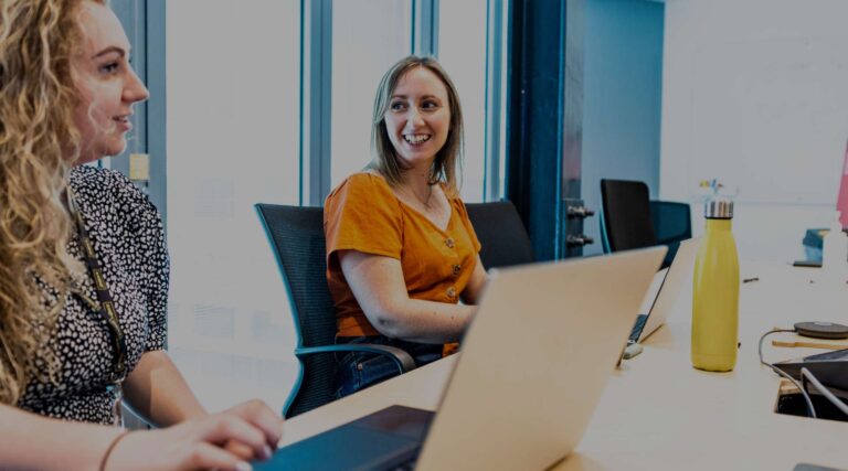 Ensono employees smiling at conference tables.